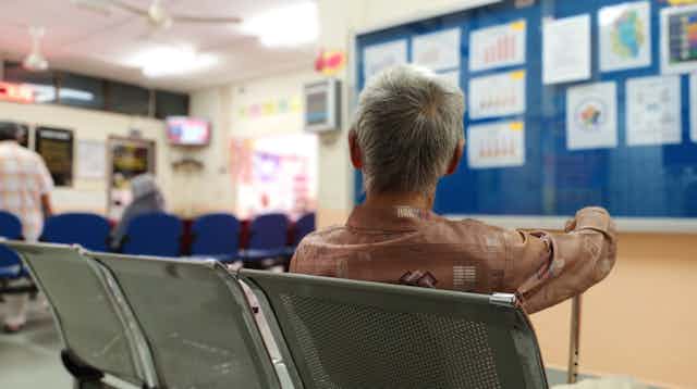 Person with cane sits in hospital waiting room