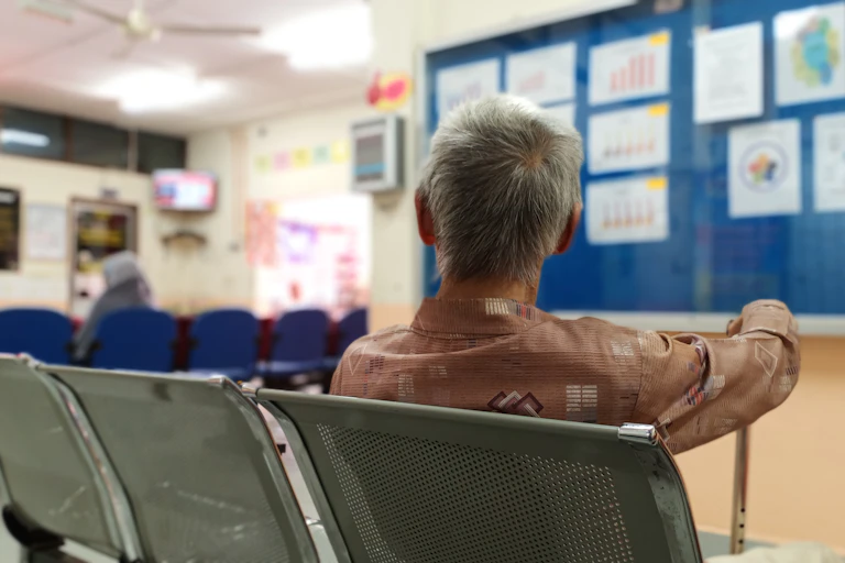 Person with cane sits in hospital waiting room