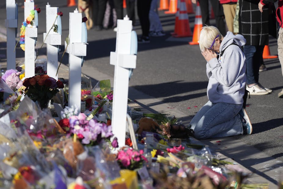 Person praying at a makeshift memorial for the victims of a mass shooting at a gay nightclub in Colorado, US
