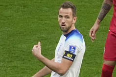 A football player in a white shirt wearing a black armband with yellow lettering that reads: No discrimination.