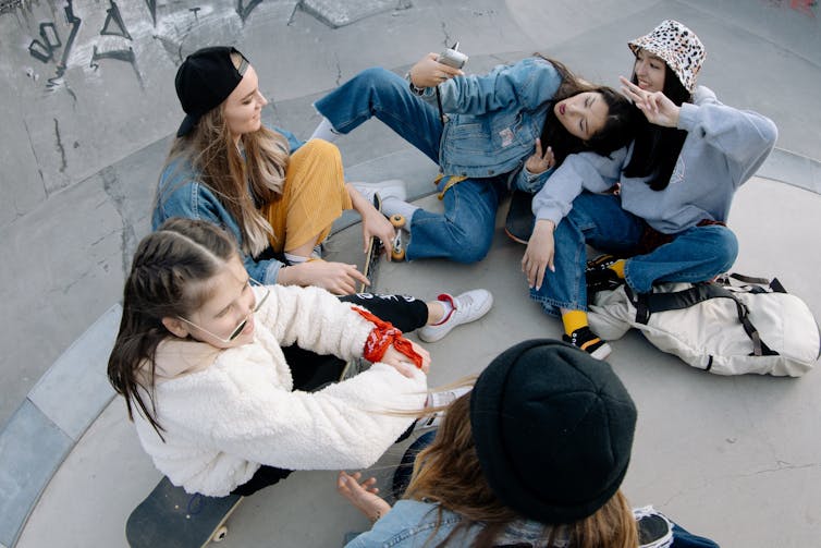 group of teen girls sit in skate park