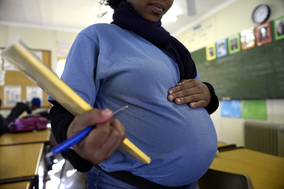 A pregnant lady wearing a blue short and holding a pen and notebook