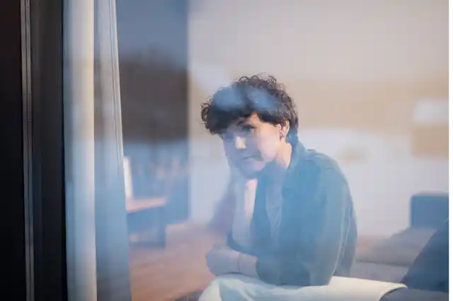 A young woman looks pensively out the window.