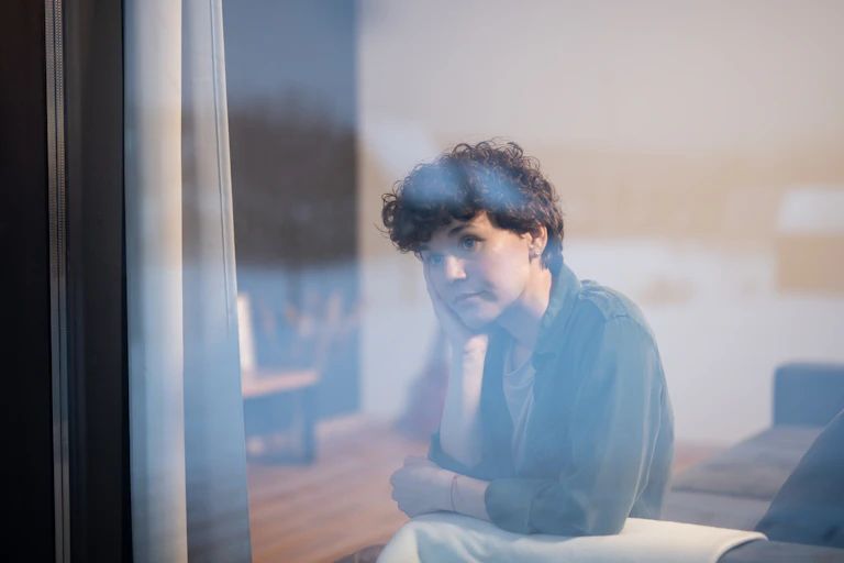 A young woman looks pensively out the window.