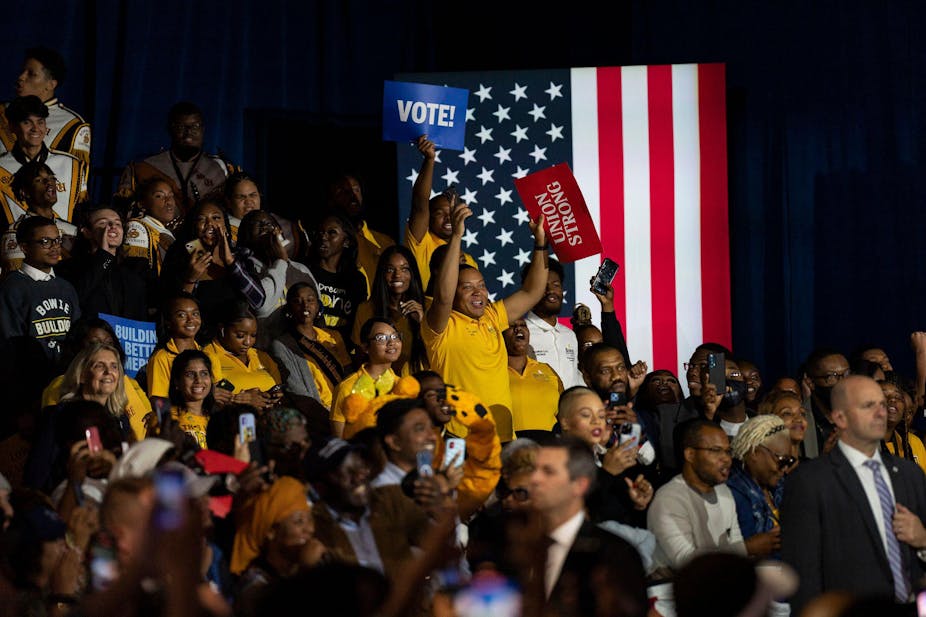 Young black voters gather at a rally during the US midterms waving posters marked vote.