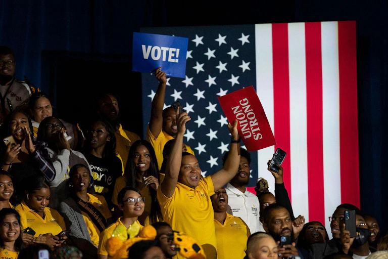 Young black voters gather at a rally during the US midterms waving posters marked vote.