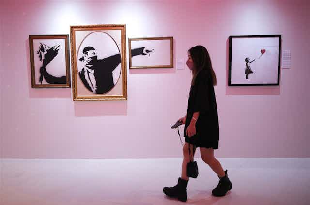 A woman walks past Banksy’s artwork ‘Flower thrower '
