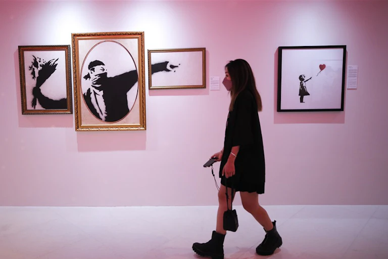 A woman walks past Banksy’s artwork ‘Flower thrower '