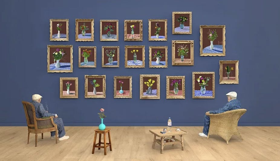 Man sitting admiring flower paintings on a wall.