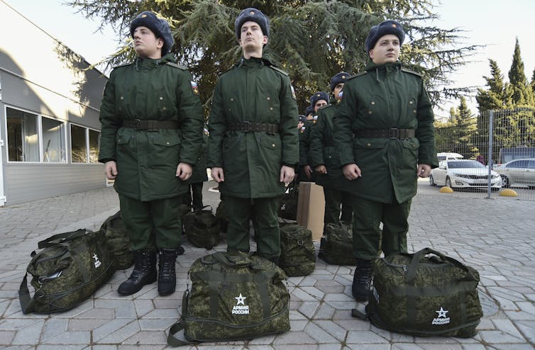 Russian conscripts stand at attention with their kit bags.