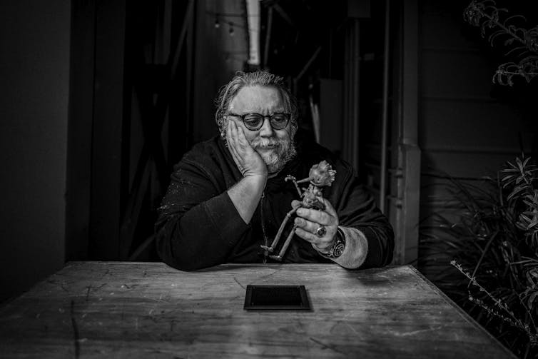In a black and white photo, Guillermo del Toro holds the primary puppet used for his stop-motion Pinocchio.