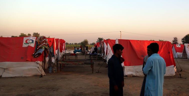 Two people stand before rows of red and white tents.
