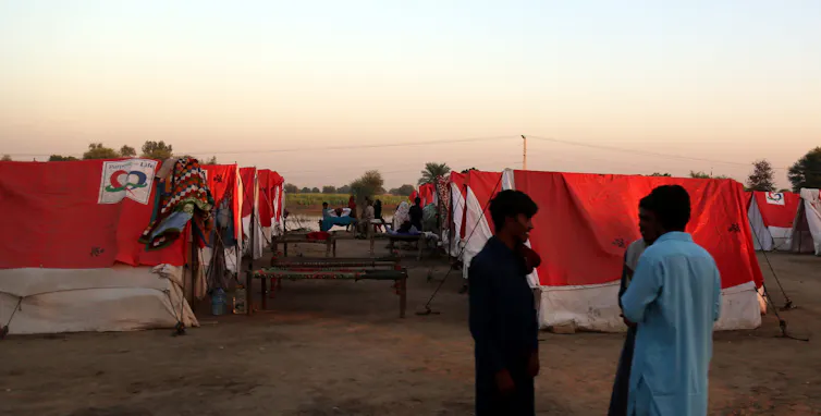 Two people stand before rows of red and white tents.