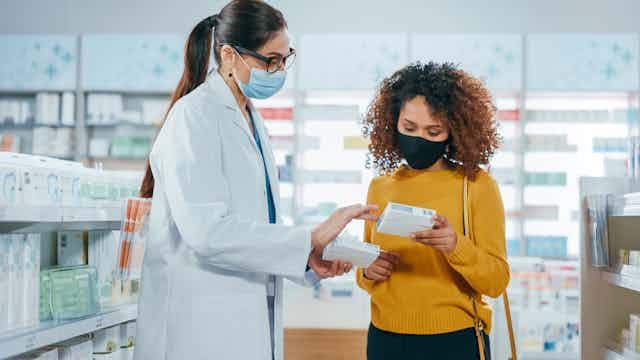 Pharmacist talks to woman about the medicine she is holding