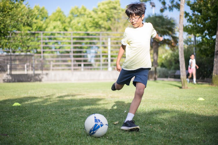 A kid plays soccer.