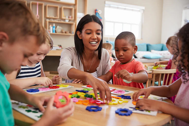 Preschool teacher and children play with shapes
