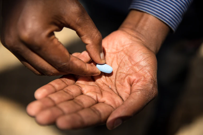 A close up of a blue pill in man's palm.