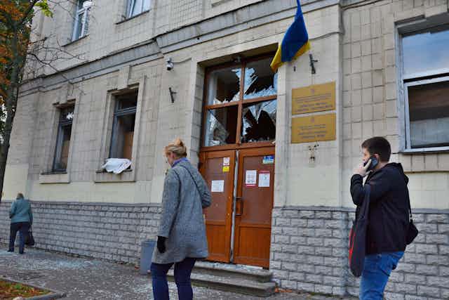 Ukrainians walk past a Kyiv medical centre that has been hit by a Russian missile.