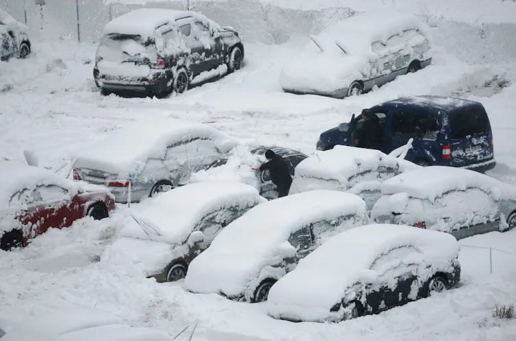 Cars covered in snow in a car park.