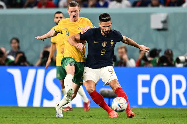 L’attaquant français Olivier Giroud à la lutte avec le défenseur australien Kye Rowles, lors de la Coupe du monde de football 2022, au Qatar.