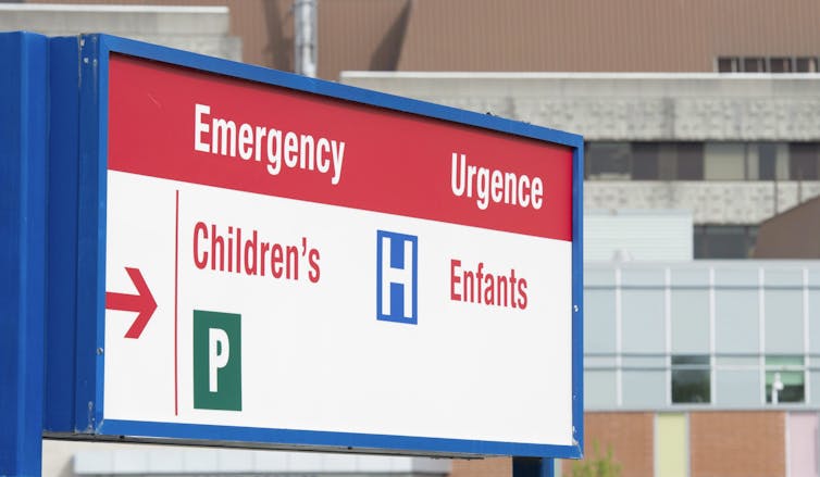 a hospital sign directing people to EMERGENCY CHILDREN / URGENCE ENFANTS. Hospitals are overwhelmed with cases of RSV.