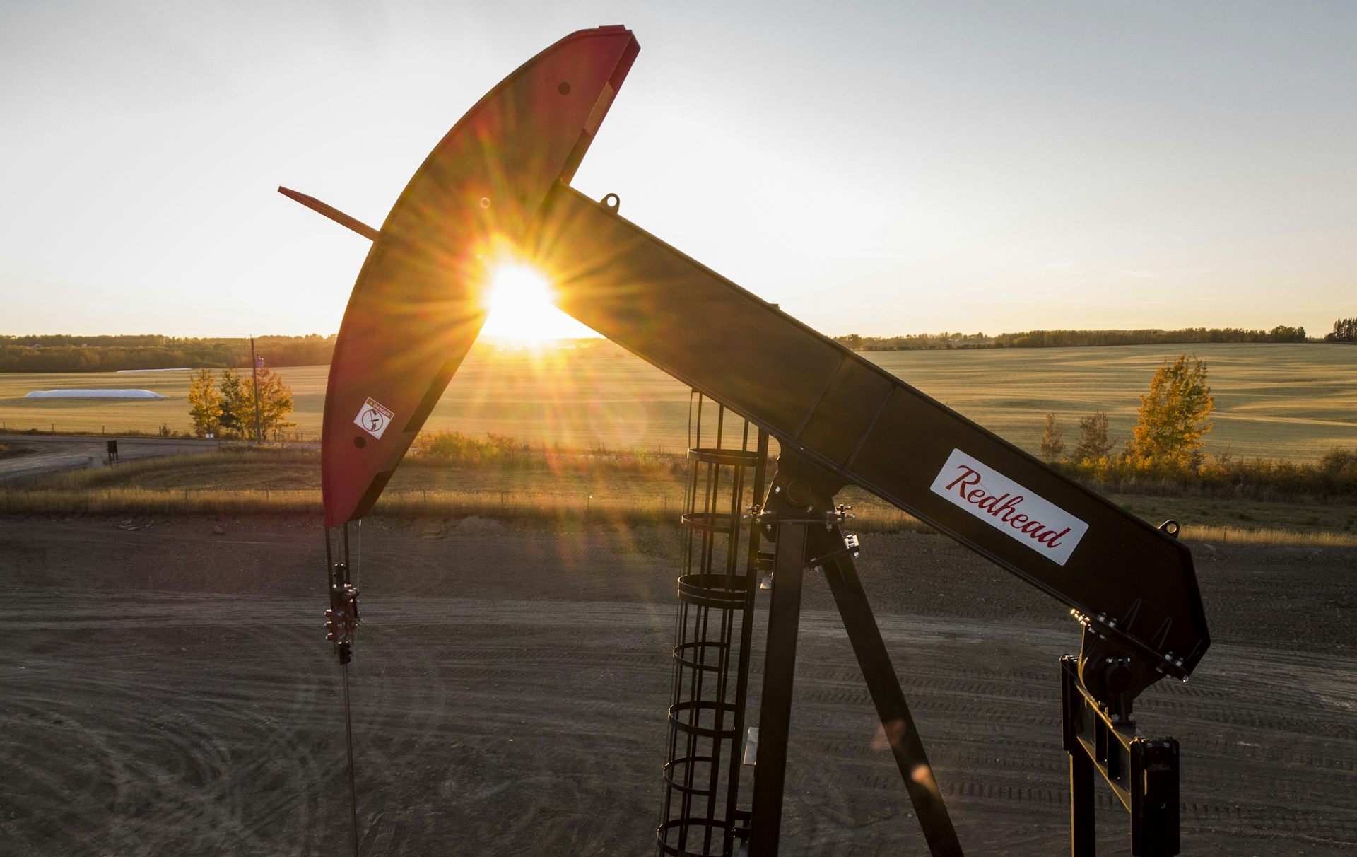 A pumpjack drawing oil out of the ground with the sun setting behind it