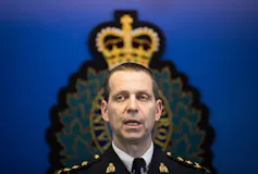 A man speaks standing in front of a insignia that makes it look as though he has a crown on his head.