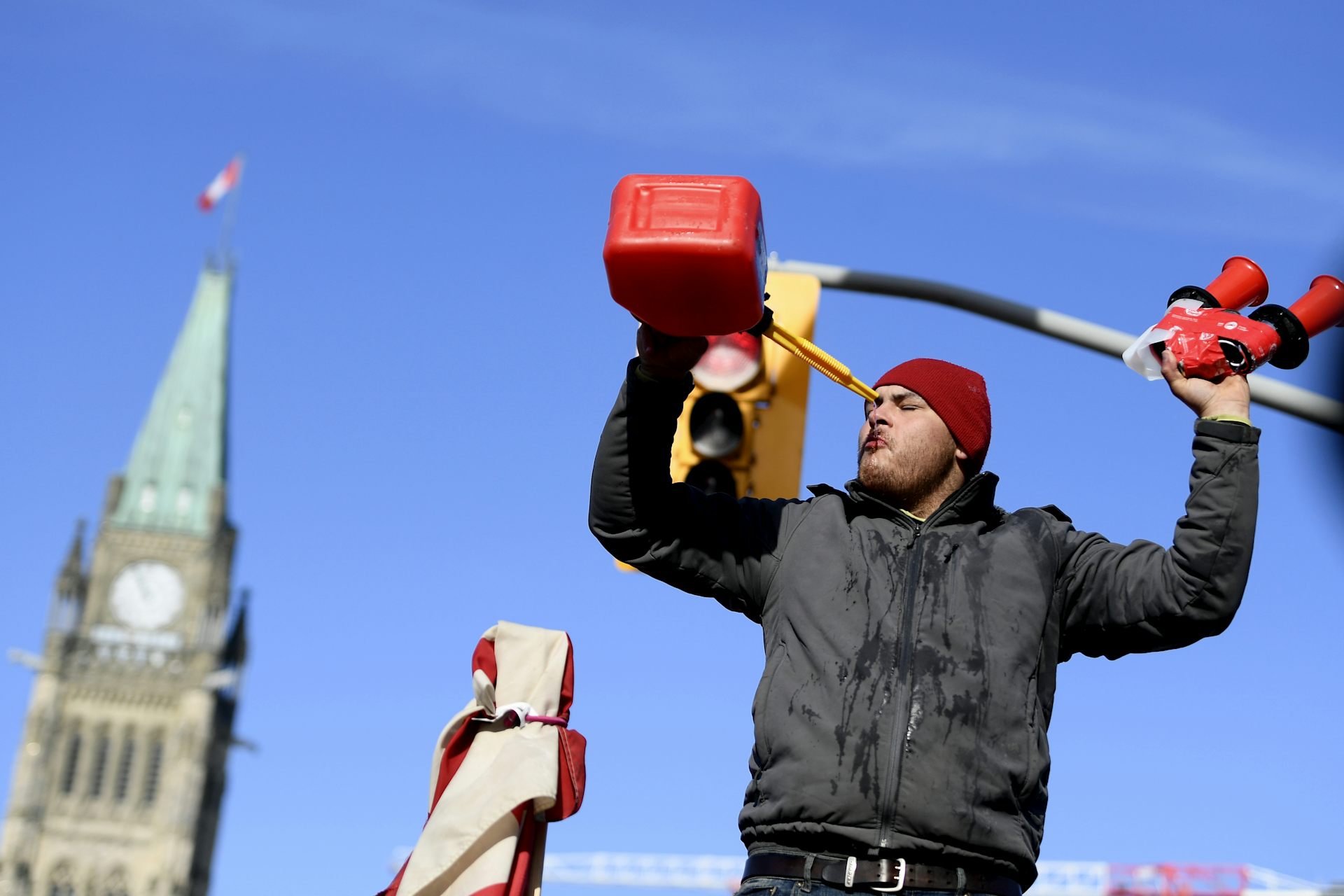 A protest drinks Gatorade from a fuel container with the Peace Tower in the background.