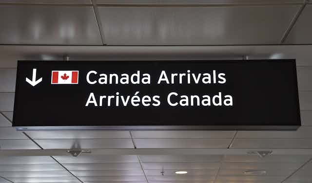A sign that reads: Canada arrivals with a Canadian flag.