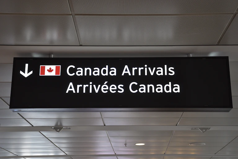 A sign that reads: Canada arrivals with a Canadian flag.
