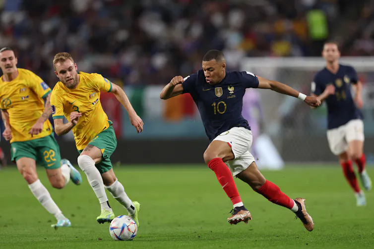 Photo de l’attaquant français Kylian Mbappé prenant l’avantage sur le milieu de terrain australien Nathaniel Atkinson durant le match de pool de la Coupe du monde 2022 Doha, au Qatar.