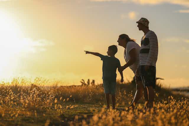 Couple with child pointing at sunset