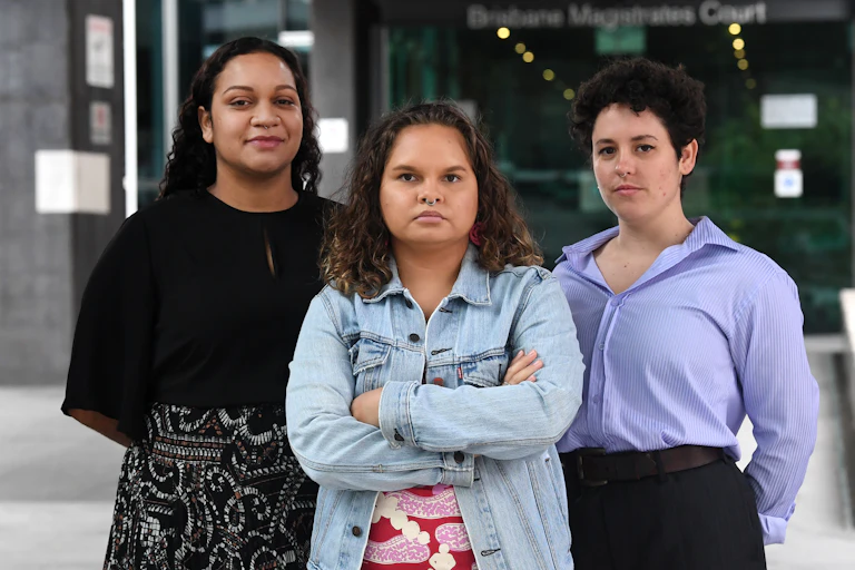 Three young women standing together, looking at the camera