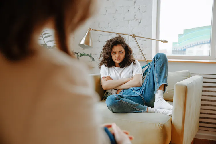 A girl looks grumpy on the couch.