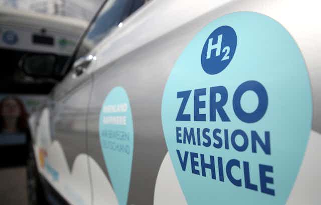 A close-up of a hydrogen car with a large "zero emission vehicle" sign on the door.