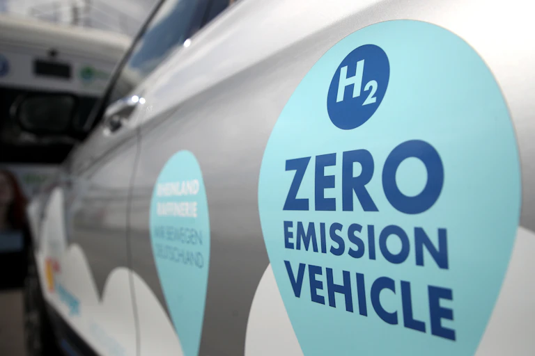 A close-up of a hydrogen car with a large "zero emission vehicle" sign on the door.