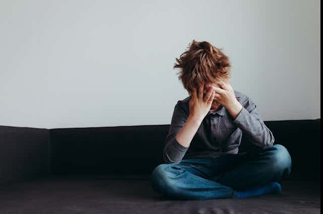 A boy with his head in his hands.