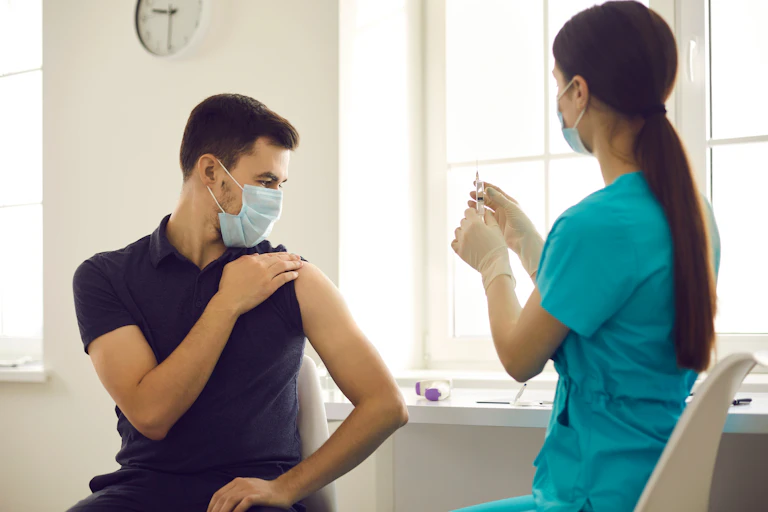 A female healthcare worker prepares to vaccinated a young man.