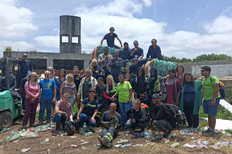 A group of people posing in front of a building with plastic waste strewn on the ground.