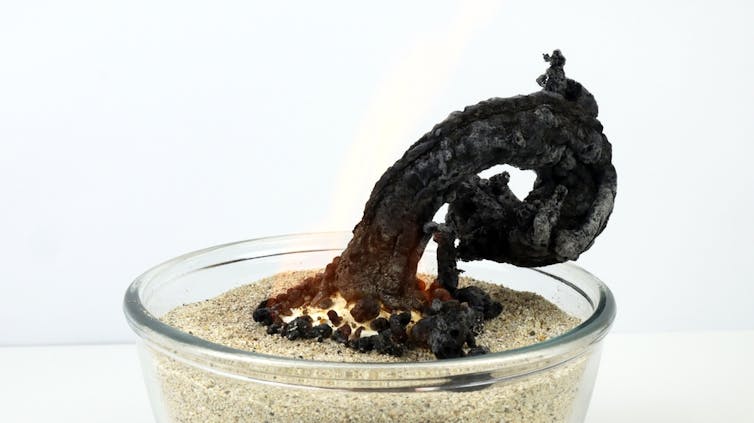 A bowl with sand and a dark curled burnt object on top