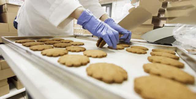 Baker worker putting packing cookies.