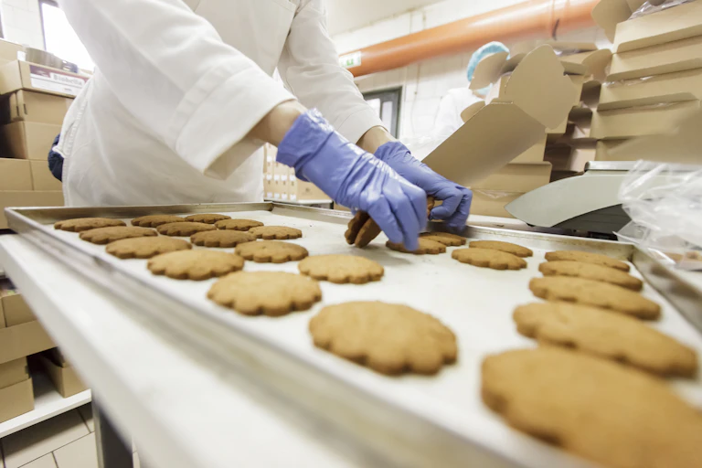Baker worker putting packing cookies.