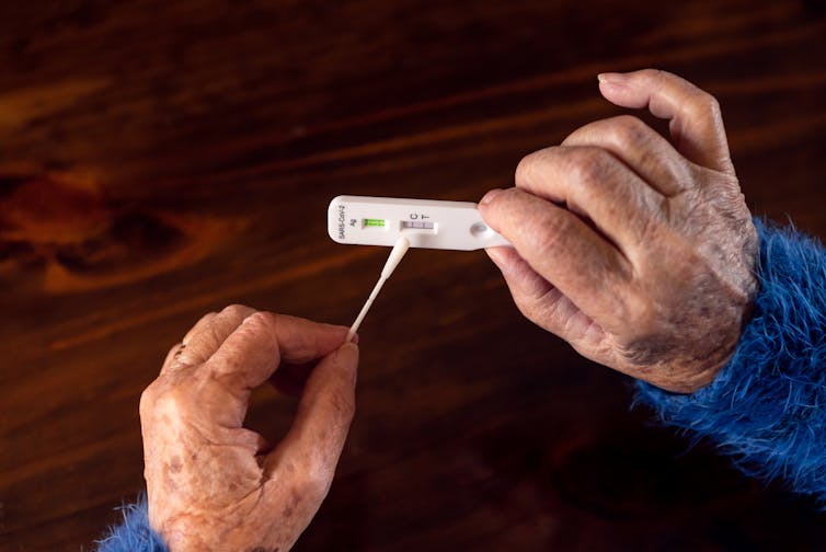 Older person holds a positive RAT