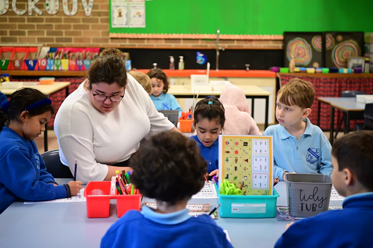 A teacher and kindergarten students work at a table.