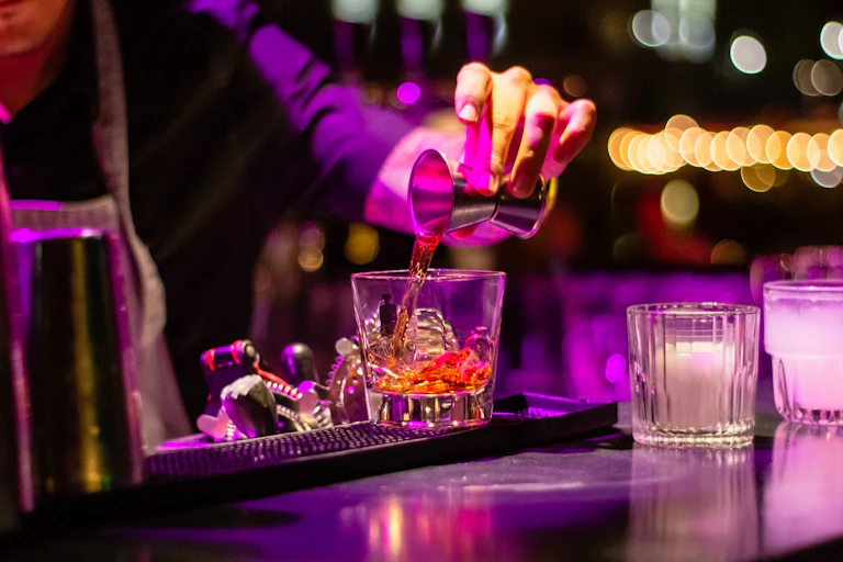 A person pouring a shot into a cocktail glass