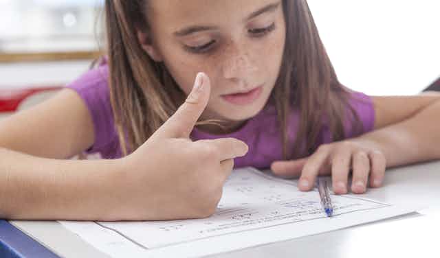 Girl doing maths homework counting on fingers