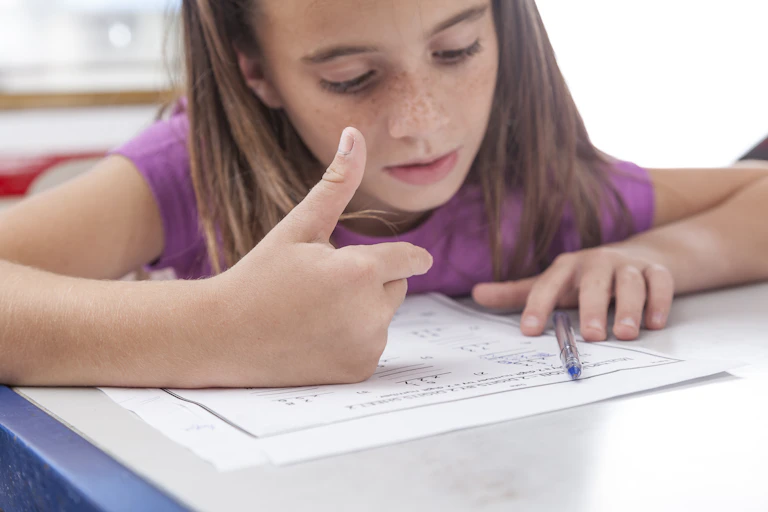 Girl doing maths homework counting on fingers