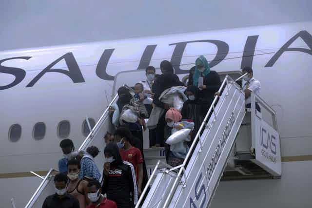 Passengers disembark from an aeroplane