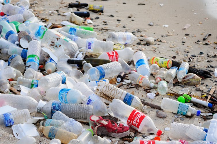 Plastic bottles strewn on a sandy beach.