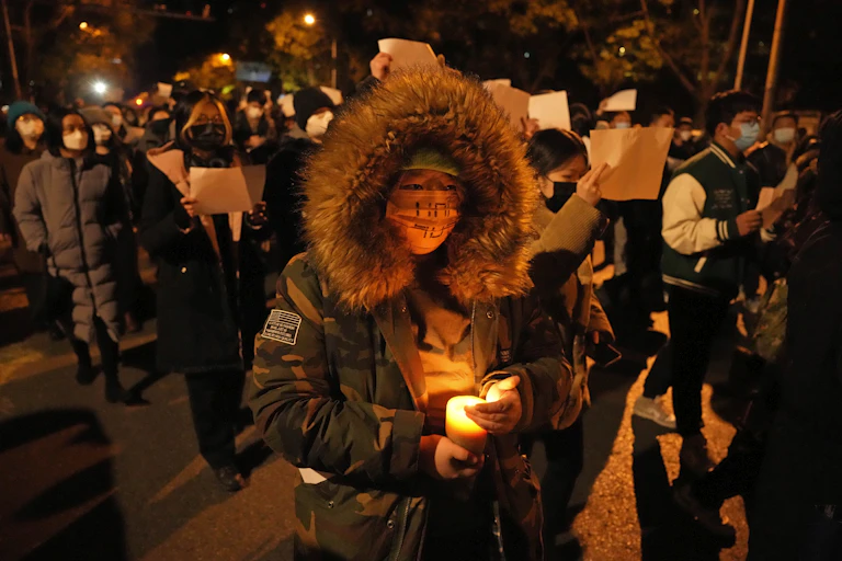 personne avec un manteau et un capuchon sur la tête tient une bougie